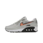 Grey Nike Air Max 90 sneakers with black and orange Swoosh accents, showcasing bold contrast and modern style.