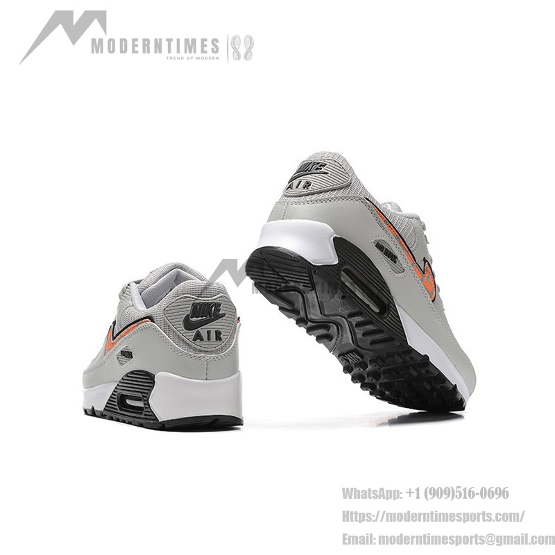 Grey Nike Air Max 90 sneakers with black and orange Swoosh accents, showcasing bold contrast and modern style.