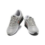 Grey Nike Air Max 90 sneakers with black and orange Swoosh accents, showcasing bold contrast and modern style.