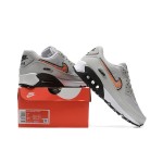 Grey Nike Air Max 90 sneakers with black and orange Swoosh accents, showcasing bold contrast and modern style.